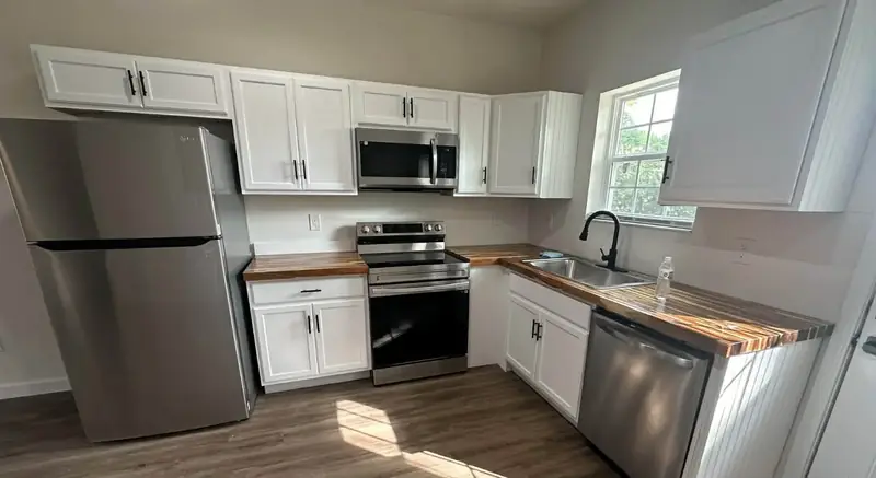 Barkley Apartment Project: kitchen with stainless appliances, white cabinets and wood countertop