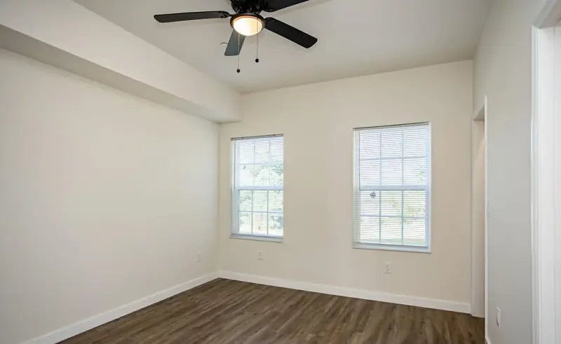 Barkley Apartment Project: finished room with two windows, ceiling fan and hardwood floor