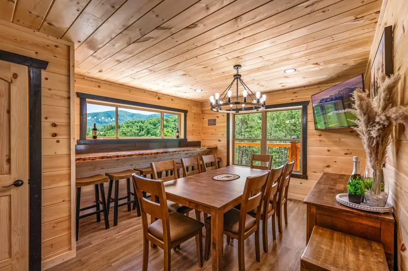 Cabin Project: wood dining room with a large table, chandelier and windows to the trees