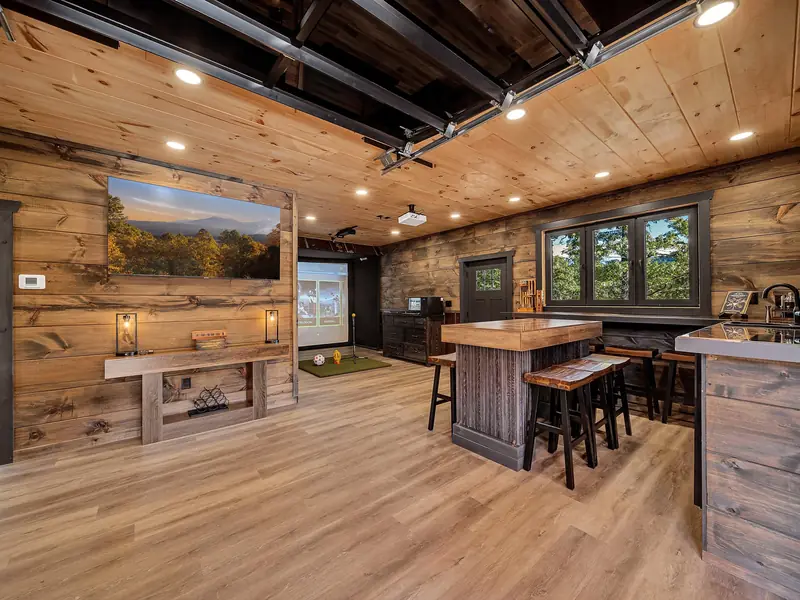 Cabin Project: rustic wood-paneled game room with a pool table, bar seating and kitchen area