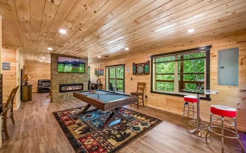 Cabin Project: wood-paneled living room with a stone fireplace and pool table