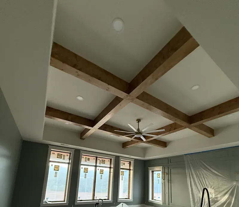 Coffered wood beam ceiling with a fan and a row of windows, finish stage in progress
