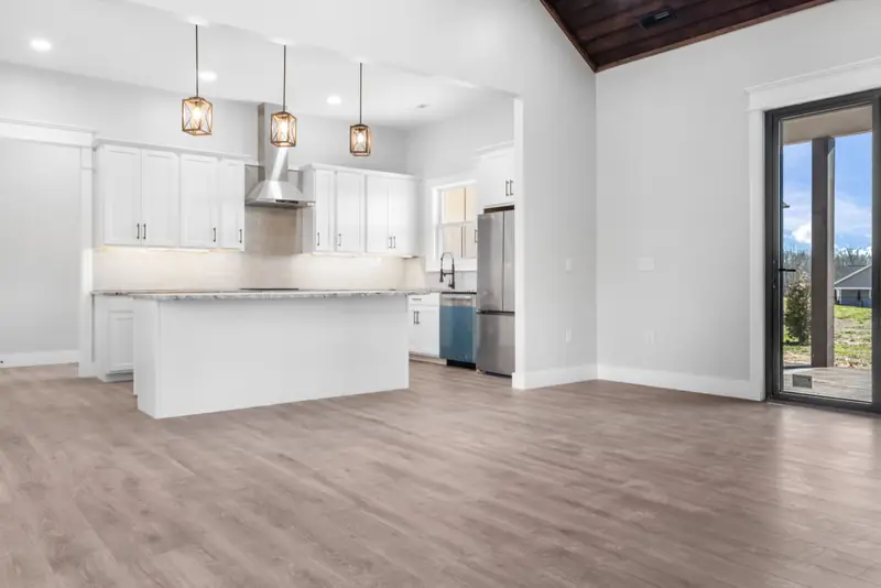 Open white kitchen with a large island, pendant lights and a wood tongue-and-groove ceiling