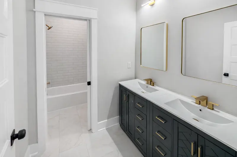 Shiloh Project: bathroom with double vanity, gold fixtures and a white brick-tile shower