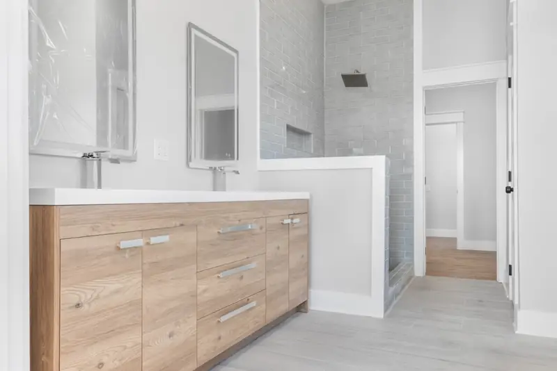 Shiloh Project: bathroom with a wood vanity, two mirrors and a gray tile shower