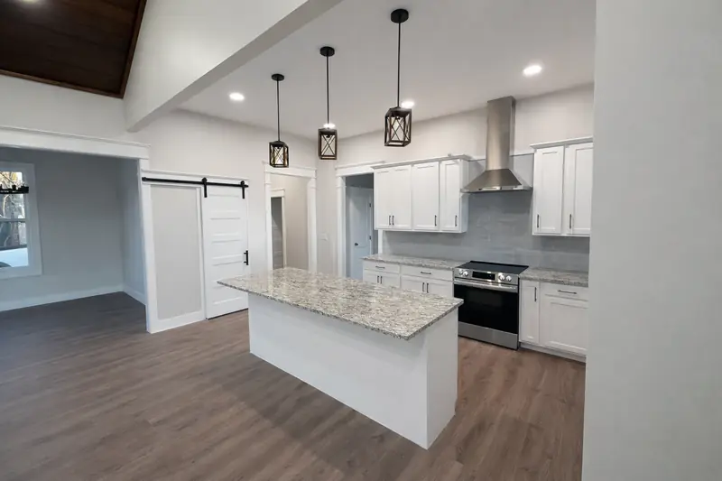 Shiloh Project: kitchen with white cabinets, granite island, range hood, pendant lights and a barn door