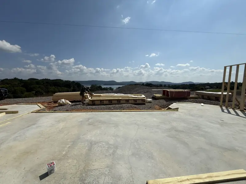 Concrete slab with a lumber delivery and the first wall going up, overlooking a lake and mountains