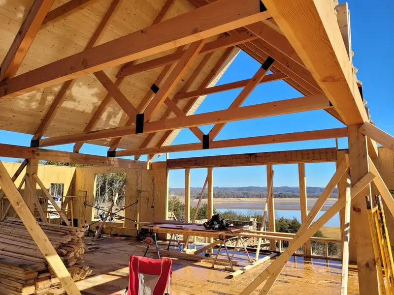 Heavy timber roof framing and open gable looking out over a lake