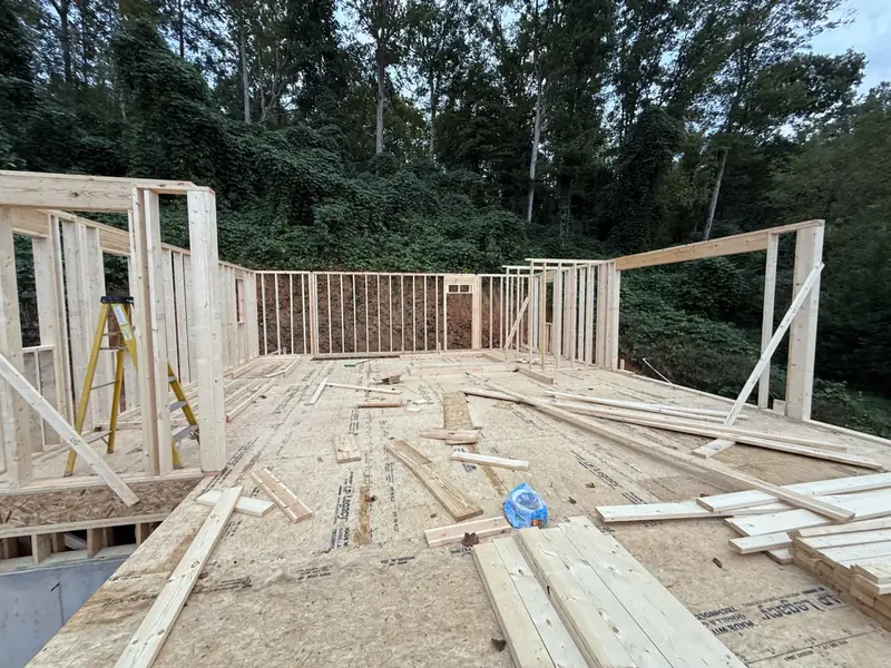 First-floor wall framing going up on a wooded hillside lot